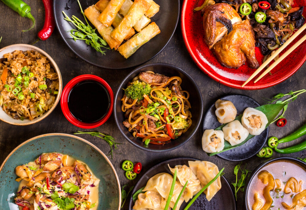 Everything You Need Near Alexan Tempe - Chinese food dark background. Chinese noodles, rice, dumplings, peking duck, dim sum, spring rolls